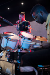 Side view portrait of contemporary music band performing on stage in club