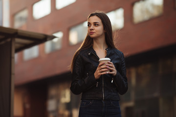 Obraz premium Beautiful woman holding paper coffee cup and enjoying a walk in the city