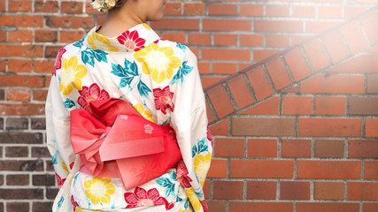 Back of japanese woman in kimono with red brick back ground.