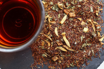Still life, aromatic dry tea with fruits and petals, close up on with a cup of tea on white...