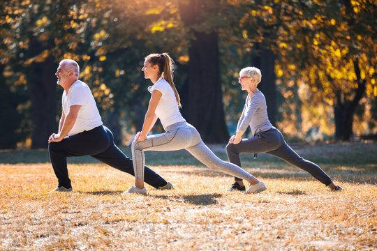 Senior man and woman and young female instructor  workout on fresh air. Outdoor activities, healthy lifestyle, strong bodies, fit figures. Stylish, modern sportswear. Different generations