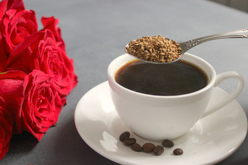 Close-up of a Cup of black instant coffee on the table , a bouquet of red roses