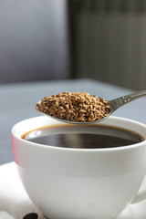 Close-up of a white Cup of coffee, ground coffee in a spoon.The process of making coffee. Copy space.