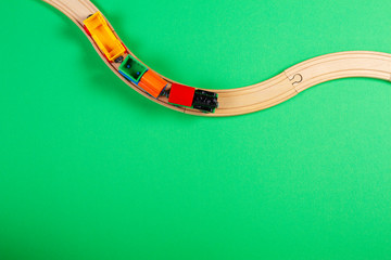 Toy train and wooden rails on green background
