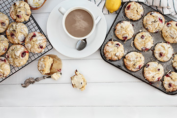 Hot steaming coffee and cranberry muffins with butter over a rustic white table background. Image shot from above with free space for text.