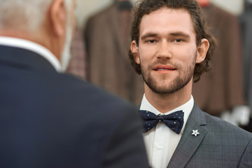 Hadsome young guy in jacket and bow tie looking at camera.