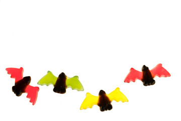 multicolored gummy jelly bat candies over white background