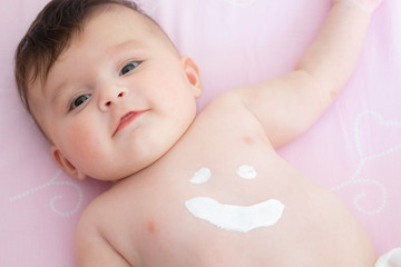 Cute baby with body cream on tummy