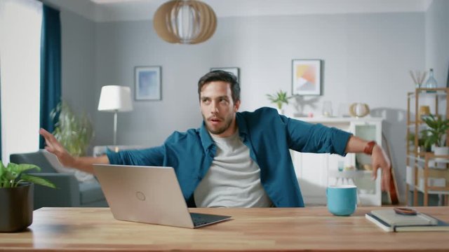 Handsome Happy Man Does Funny Dance Routine while Sitting at His Desk in the Living Room. 