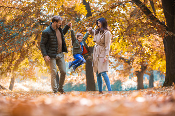 Young family having fun in the autumn park with his son.