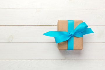 Beautiful gift box with a blue bow on the white wooden table. top view