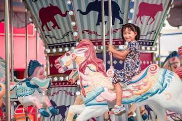 Fototapeta na wymiar kids and Carousel . little girl is happy, enjoy playing the carousel horse During the weekend of family fun In the amusement park.