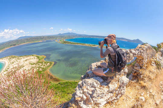 Travel female takes shots of scenic Voidokilia Beach from Navarino Castle ruin in Pylos, Peloponnese, Greece after hiking.Hiker woman photographing a popular greek landmarks. Fish eye view