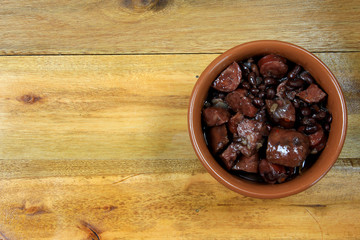 pot with feijoada, traditional brazilian cuisine dish, isolated under wooden background, top view
