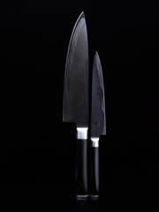 Still life of two Japanese knives with black handle and dark blade