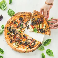 Cercles muraux Pizzeria Summer dinner or lunch. Flat-lay of people's hands taking freshly baked Italian vegetarian pizza with vegetables and fresh basil over white marble table, top view, square crop