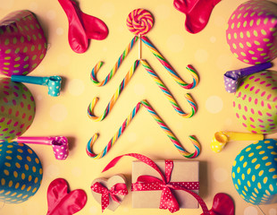 Concept of Christmas tree made of colourful candies/gifts,balls,holiday hats /flat lay top view