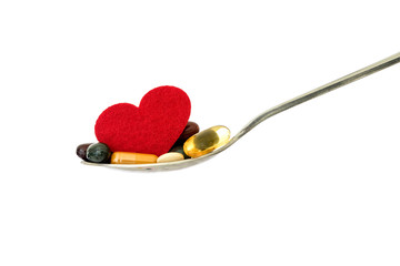 the colorful medical supplement and drug pills with red heart in spoon , pharmaceutical cardiology drugs for heart health care disease concept
