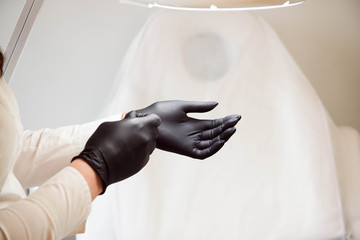 doctor beautician wears sterile black gloves prepares to receive clients