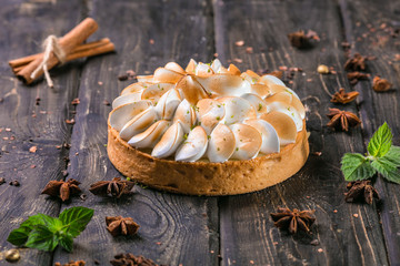 apple tart with meringue and lime peel on a wooden stand