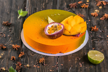 fruit mousse cake with a mango and litchi decor on a wooden stand