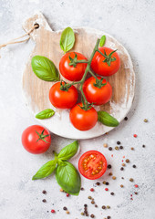 Fototapeta na wymiar Organic Cherry Tomatoes on the Vine with basil and pepper on chopping board on stone kitchen background.