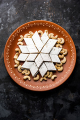 Kaju Katli is a Diamond shape Indian sweet made using cashew sugar and mava, served in a plate or bowl over moody background. selective focus