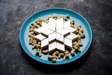 Kaju Katli is a Diamond shape Indian sweet made using cashew sugar and mava, served in a plate or bowl over moody background. selective focus