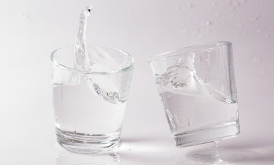 Glasses of water falling and jumping with splashes and drops	