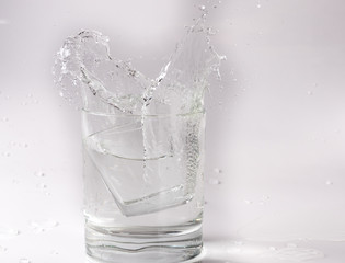 Falling and crashing glass of water. Shards of glass and splashing water