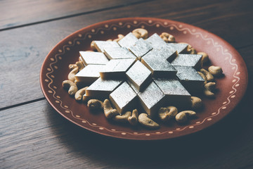 Kaju Katli is a Diamond shape Indian sweet made using cashew sugar and mava, served in a plate or bowl over moody background. selective focus