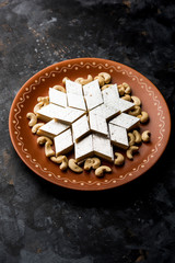 Kaju Katli is a Diamond shape Indian sweet made using cashew sugar and mava, served in a plate or bowl over moody background. selective focus