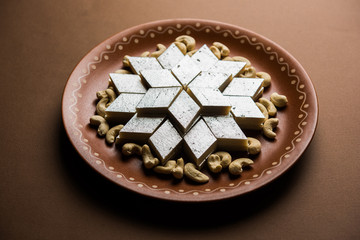 Kaju Katli is a Diamond shape Indian sweet made using cashew sugar and mava, served in a plate or bowl over moody background. selective focus