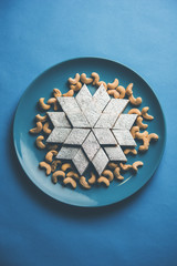 Kaju Katli is a Diamond shape Indian sweet made using cashew sugar and mava, served in a plate or bowl over moody background. selective focus