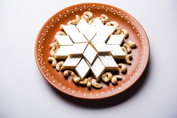 Kaju Katli is a Diamond shape Indian sweet made using cashew sugar and mava, served in a plate or bowl over moody background. selective focus