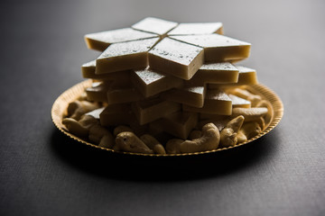 Kaju Katli is a Diamond shape Indian sweet made using cashew sugar and mava, served in a plate or bowl over moody background. selective focus