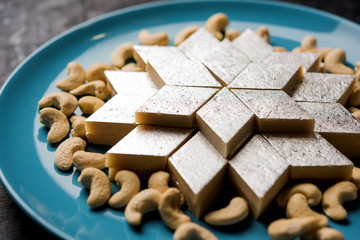 Kaju Katli is a Diamond shape Indian sweet made using cashew sugar and mava, served in a plate or bowl over moody background. selective focus