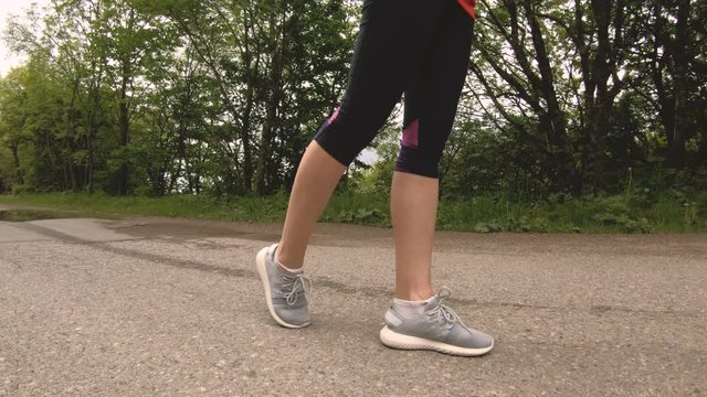 Close-up Legs of slim girl before jogging in the forest. Low angle movement around the object