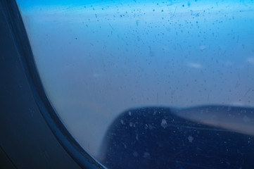 Airplane window in the air. Blurred clouds below. Illuminator transport aircraft. Tourist background