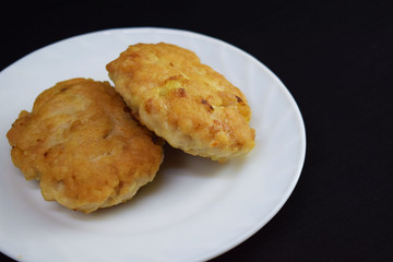 Delicious cutlets on a white plate on a black background.