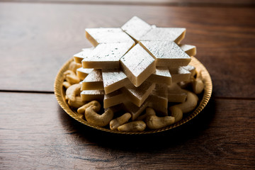 Kaju Katli is a Diamond shape Indian sweet made using cashew sugar and mava, served in a plate or bowl over moody background. selective focus