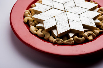 Kaju Katli is a Diamond shape Indian sweet made using cashew sugar and mava, served in a plate or bowl over moody background. selective focus