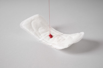 Pouring of red paint onto menstrual pad on grey background © Pixel-Shot