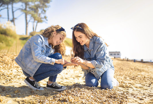 Mother and daughter collecting seashell at the beach