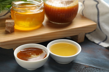 Bowls and jars of tasty honey on table, closeup