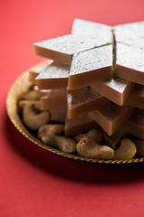 Kaju Katli is a Diamond shape Indian sweet made using cashew sugar and mava, served in a plate or bowl over moody background. selective focus