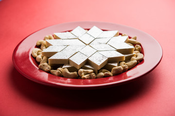 Kaju Katli is a Diamond shape Indian sweet made using cashew sugar and mava, served in a plate or bowl over moody background. selective focus