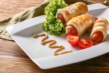 Delicious sausage rolls with sauce and vegetables on plate