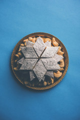 Kaju Katli is a Diamond shape Indian sweet made using cashew sugar and mava, served in a plate or bowl over moody background. selective focus