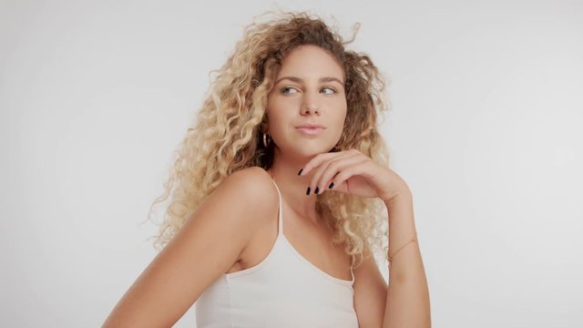 beauty model with curly blond hair blowing in air streaming in air